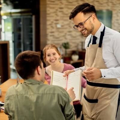 Un homme lit la carte d'un restaurant pour choisir son repas. 